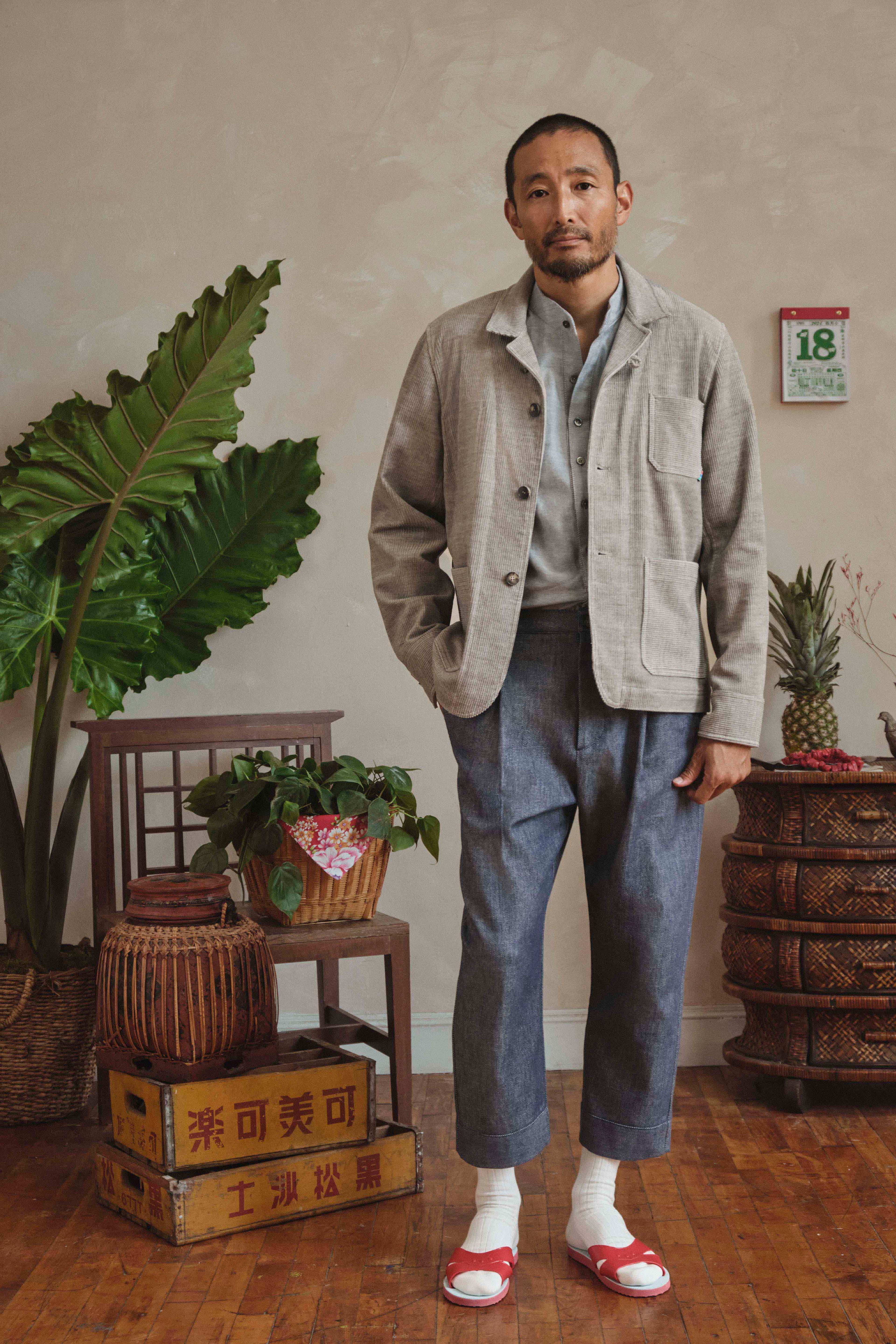 Model standing in a room with plants and wooden furniture
