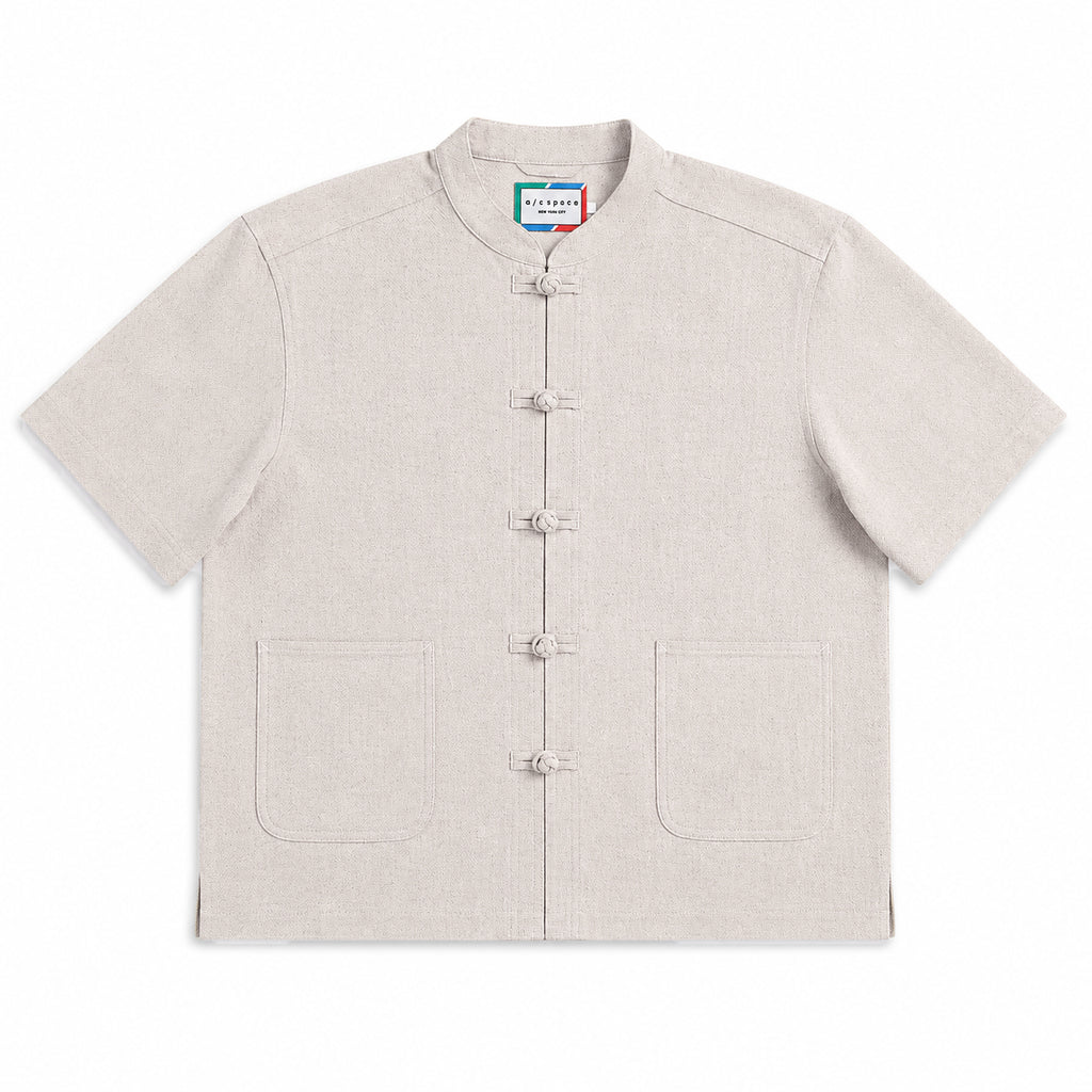A light beige short-sleeve mandarin collar shirt with five front toggle closures and two front patch pockets, shown flat on a white background.