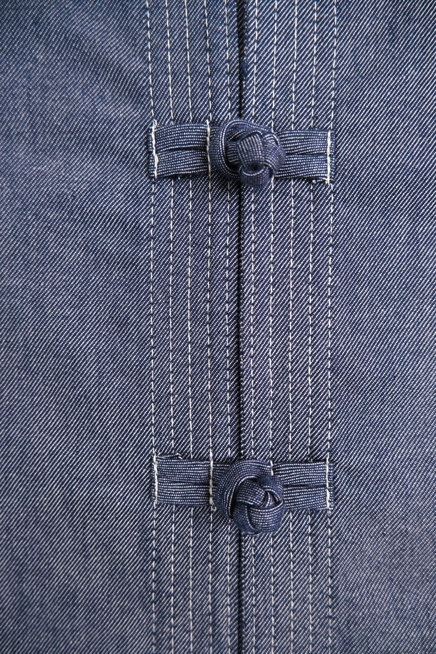Close-up of a dark gray textured fabric garment featuring two traditional Chinese-style knot buttons down the center front.